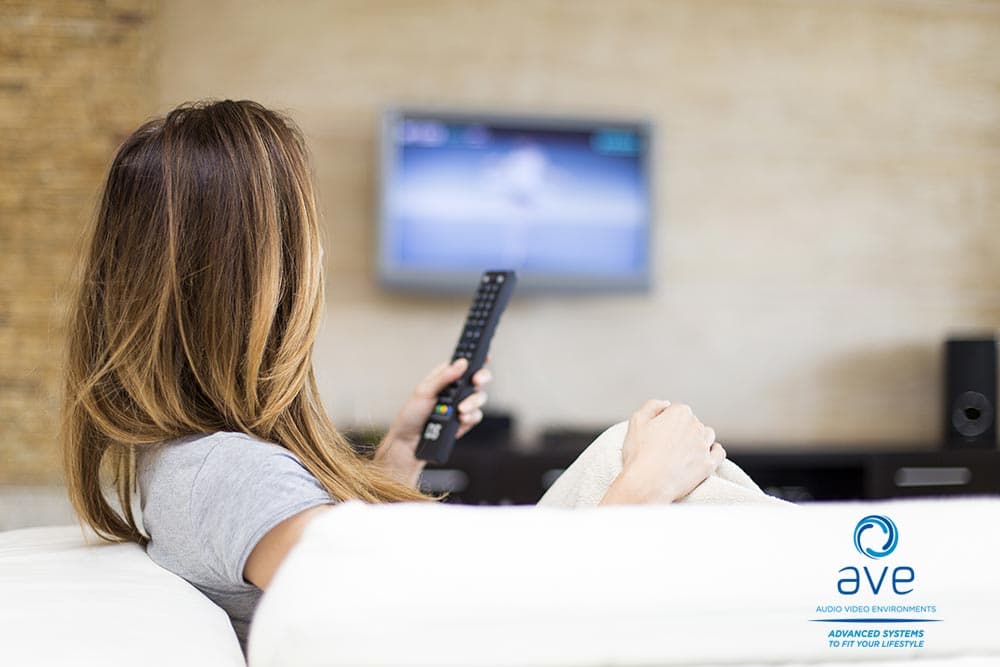 woman watching mounted tv with universal remote